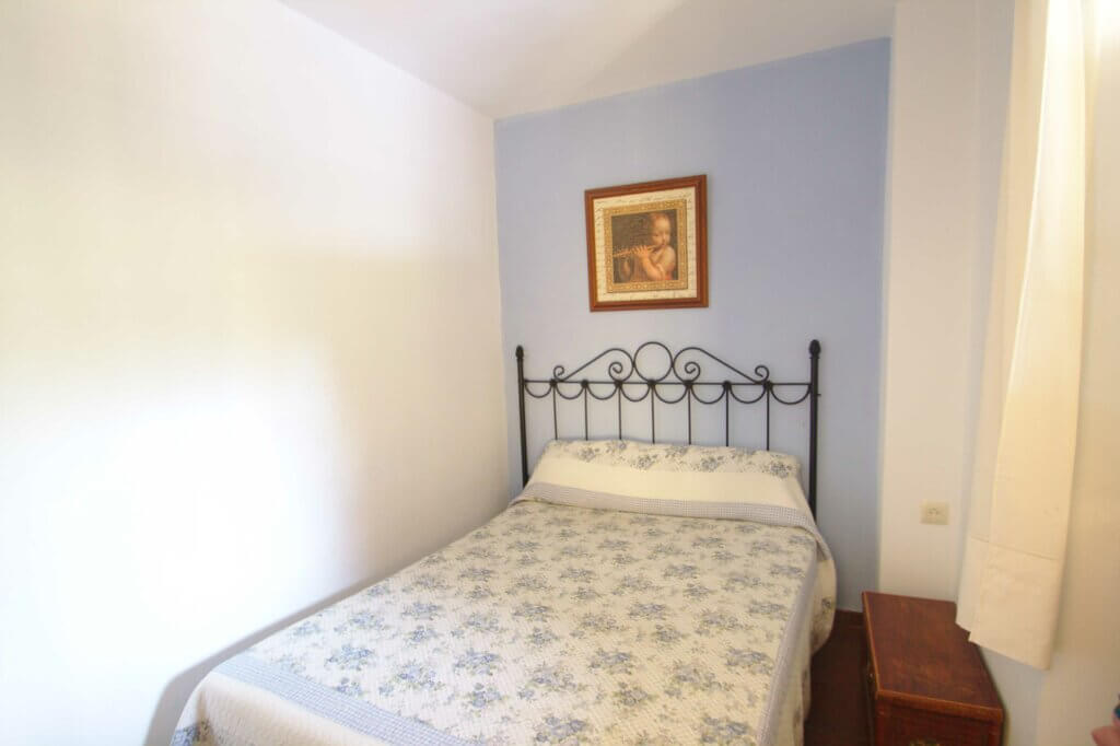 La imagen muestra una de las habitaciones de la casa amarilla, se ve la cama y la decoración en tonos claros de la habitación.
